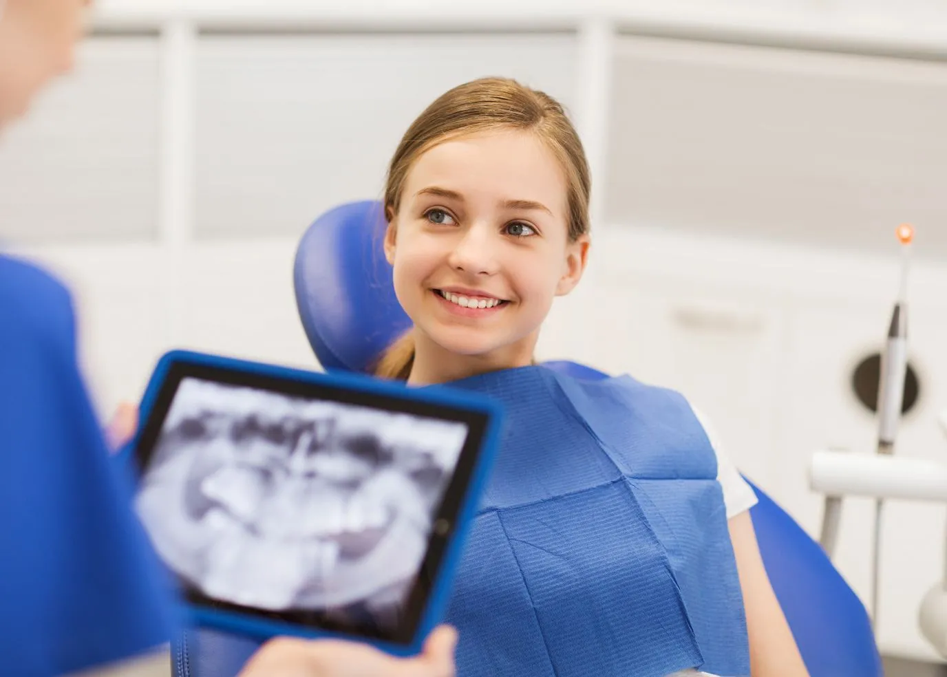 A teenage girl smiling while sitting in an exam chair