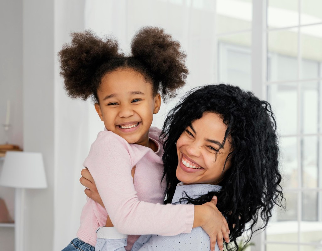 A woman lifting a child up while they're both smiling